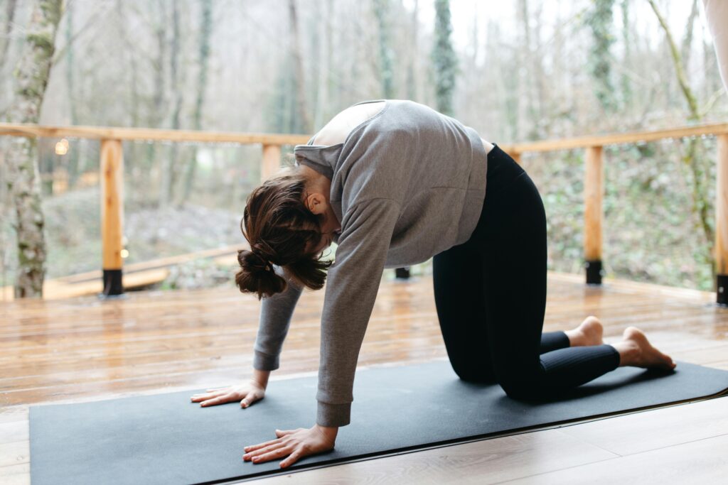 pexels-photo-7663227-7663227 A woman doing yoga on a mat surrounded by trees, enhancing mindfulness and flexibility.