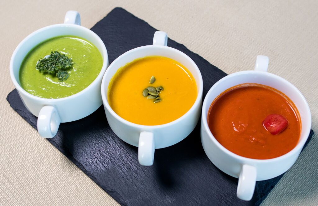pexels-photo-8738017-8738017 A variety of vegetarian soups presented in white mugs, featuring broccoli, pumpkin, and tomato flavors.